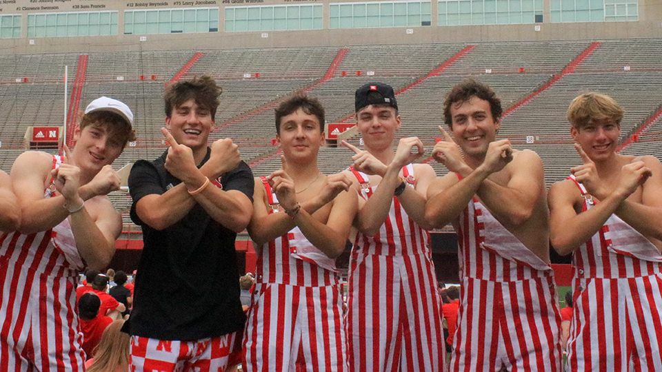 Students in red and white striped overalls display their Husker spirit in Memorial Stadium.