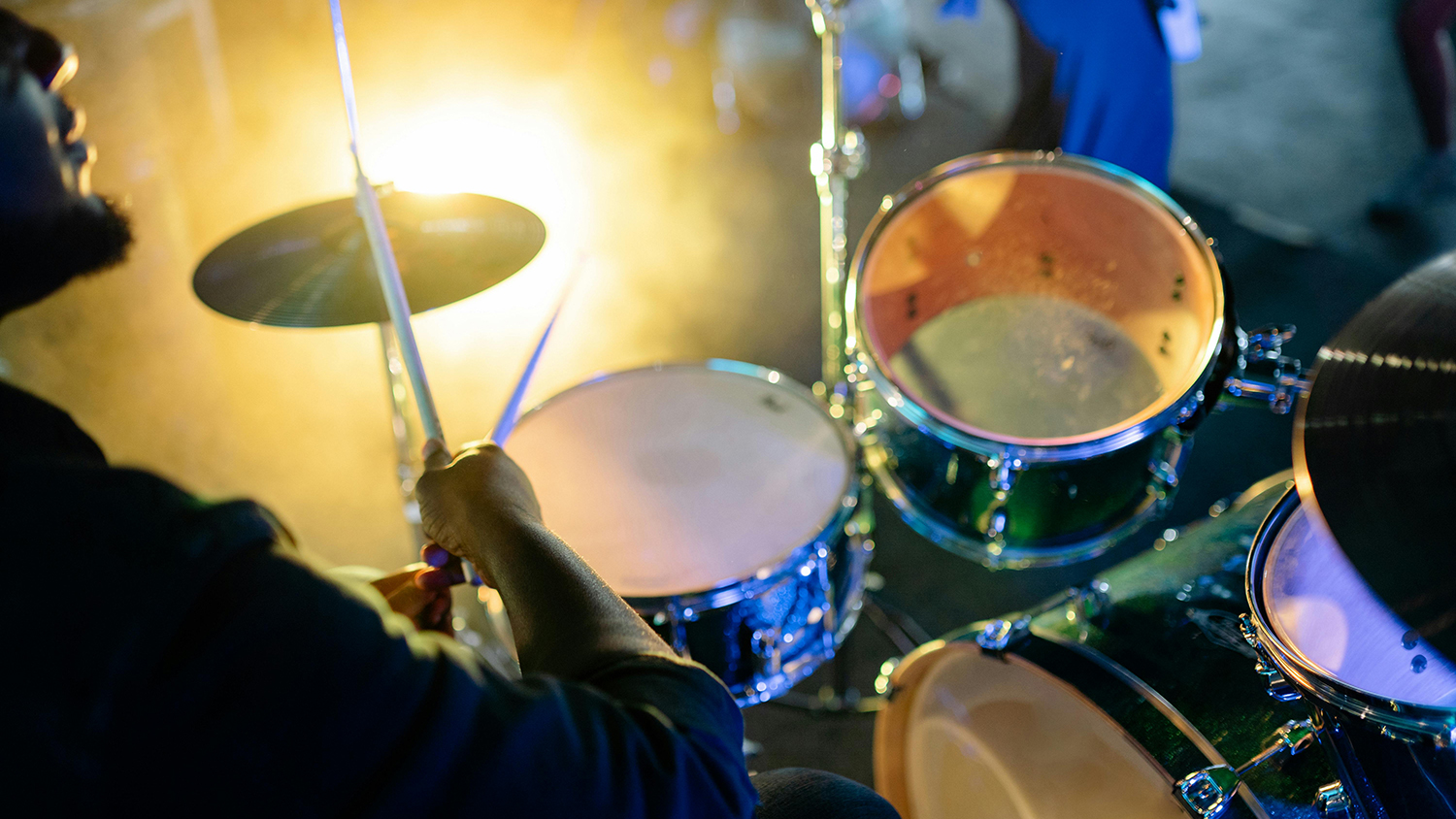 A person plays the drums on stage at a music concert. [pexels-yankrukov]