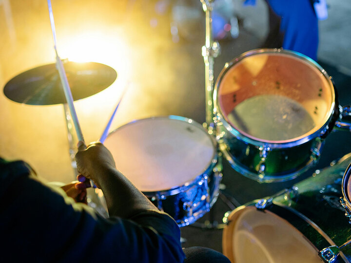 A person plays the drums on stage at a music concert. [pexels-yankrukov]