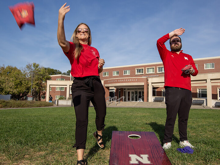 Nebraska's Hollie Swanson (left) and Logan Kahlor practice cornhole tosses while setting up the 2024 homecoming yard games competition on the Meier Commons. In her fifth year helping plan the annual celebration, Swanson is now leading the homecoming committee. [Troy Fedderson | University Communication and Marketing]