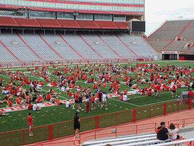 Husker football fans sit on the field in Memorial Stadium during the Husker Watch Party in 2022.